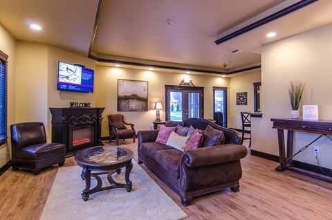 A living room with a brown leather couch and a fireplace.